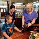 Shelton House educator shows clay jug to young visitor.